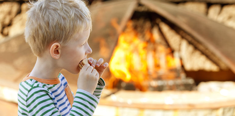 Child eating a smore by a campfire