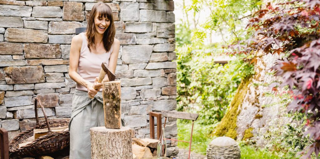 To Do List Before Lighting Your First Fire Of The Season- a woman cut her wood for the winter