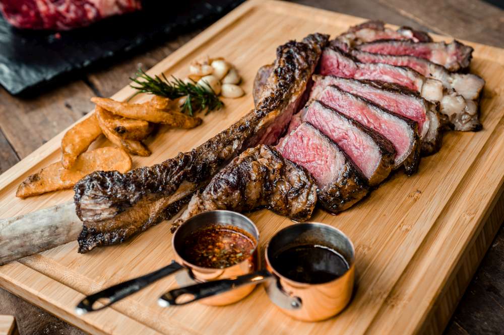 Delicious Tomahawk Steak sliced on a wood board and ready to eat. How to cook the perfect Tomahawk steak?