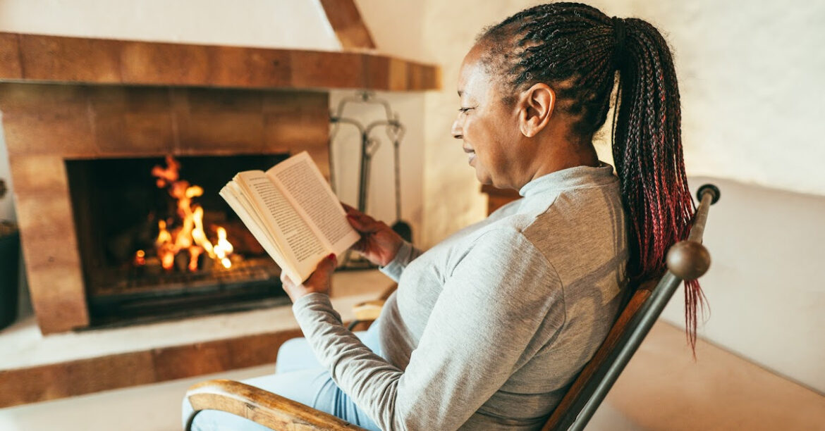 20 Cozy Fireplace Activities for Winter Enjoyment and Relaxation - a woman is reading by the fireplace