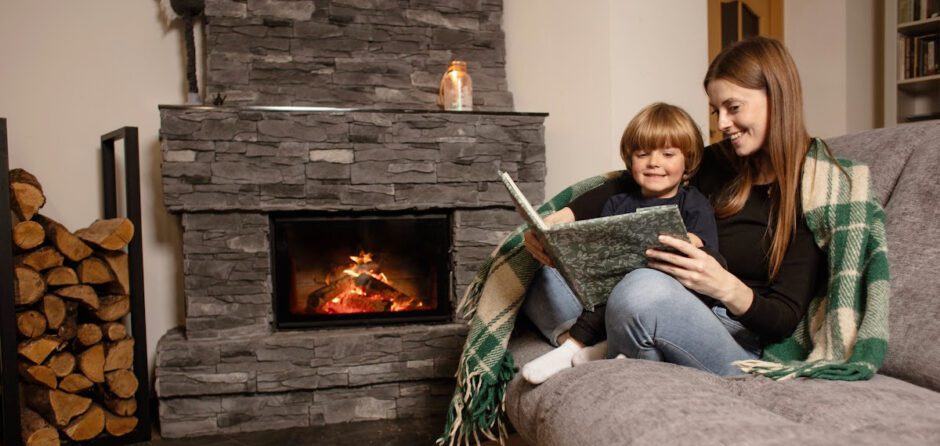 A mother and son cuddle by the fireplace reading a book while mindful of fireplace safety