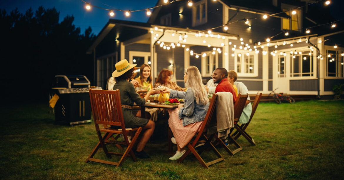 A group of friends are dining outside at night with a bbq