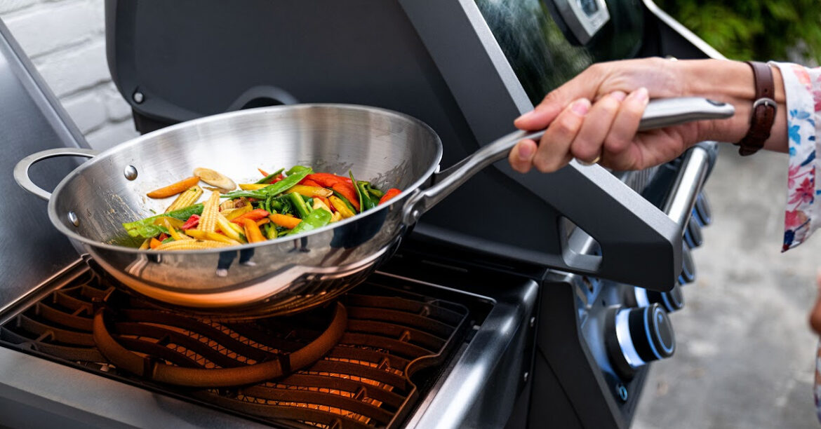 Vegetables are grilling in a wok on a bbq